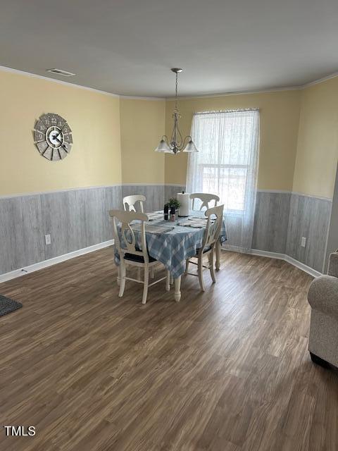 dining area featuring crown molding, an inviting chandelier, and dark hardwood / wood-style flooring