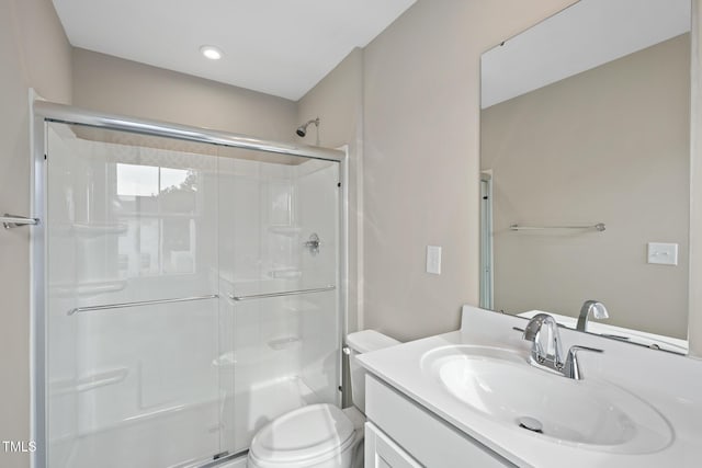 bathroom featuring toilet, vanity, and a shower with shower door