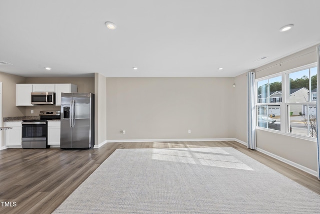 kitchen with stainless steel appliances, wood-type flooring, and white cabinets