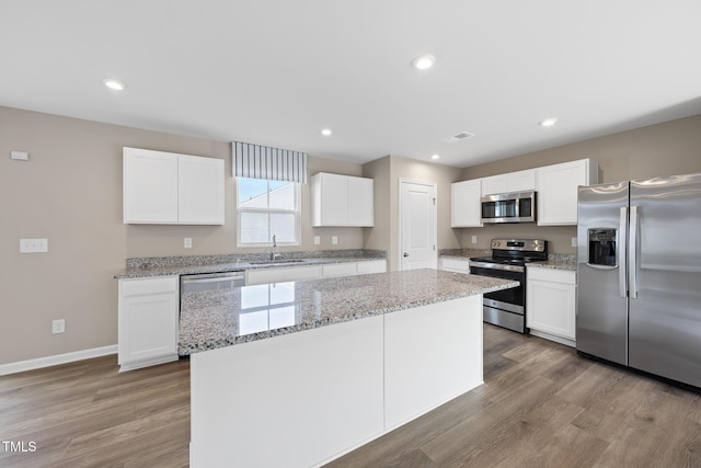 kitchen with sink, a center island, light wood-type flooring, appliances with stainless steel finishes, and white cabinets