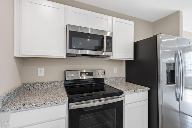 kitchen featuring stainless steel appliances, light stone countertops, and white cabinets