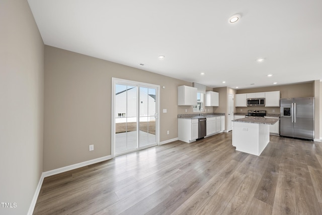 kitchen featuring white cabinetry, appliances with stainless steel finishes, a center island, and light wood-type flooring