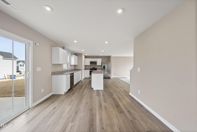 kitchen with sink, light hardwood / wood-style flooring, white cabinetry, stainless steel appliances, and a kitchen island