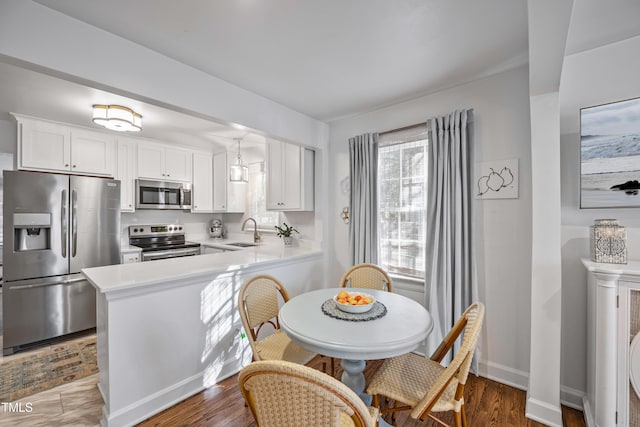 kitchen featuring appliances with stainless steel finishes, white cabinetry, kitchen peninsula, and sink