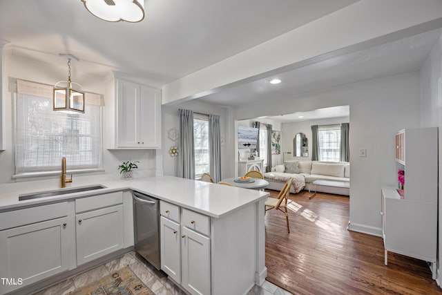 kitchen featuring kitchen peninsula, dishwasher, a healthy amount of sunlight, white cabinetry, and sink