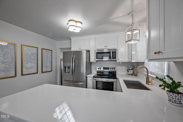 kitchen with stainless steel appliances, white cabinetry, sink, and pendant lighting