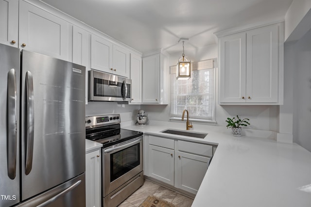 kitchen featuring stainless steel appliances, decorative light fixtures, white cabinetry, and sink