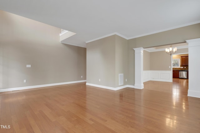 unfurnished living room with ornate columns, ornamental molding, a chandelier, and light wood-type flooring