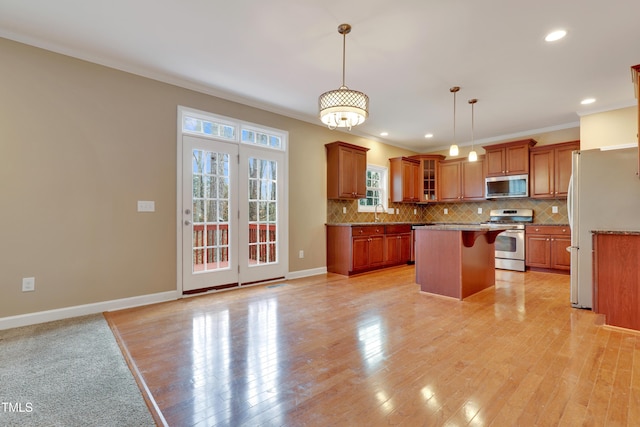 kitchen with hanging light fixtures, a kitchen bar, stainless steel appliances, a kitchen island, and decorative backsplash