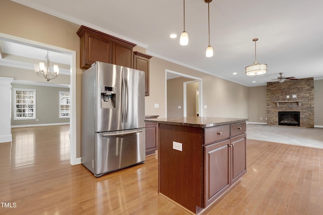 kitchen with a kitchen island, a fireplace, dark stone counters, light hardwood / wood-style floors, and stainless steel refrigerator with ice dispenser