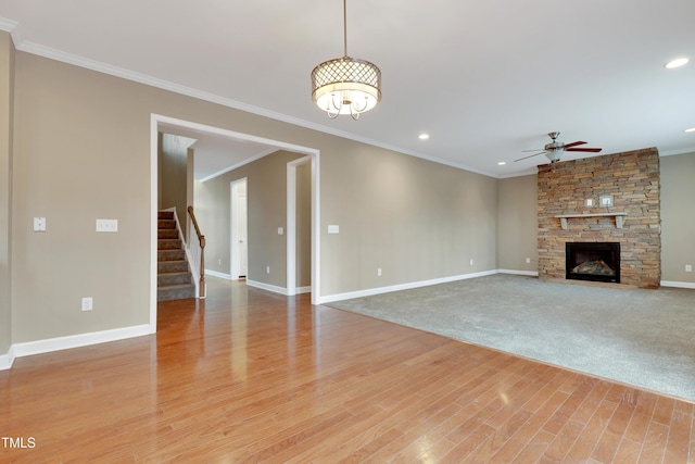 unfurnished living room featuring ceiling fan, a stone fireplace, ornamental molding, and light hardwood / wood-style floors