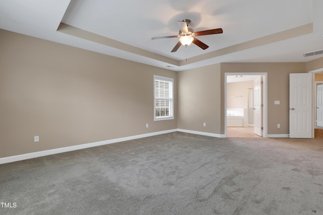 unfurnished room featuring ceiling fan, a raised ceiling, and light carpet