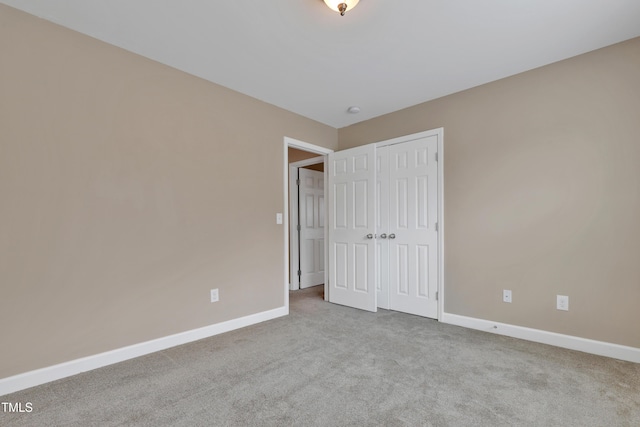 unfurnished bedroom featuring light colored carpet and a closet