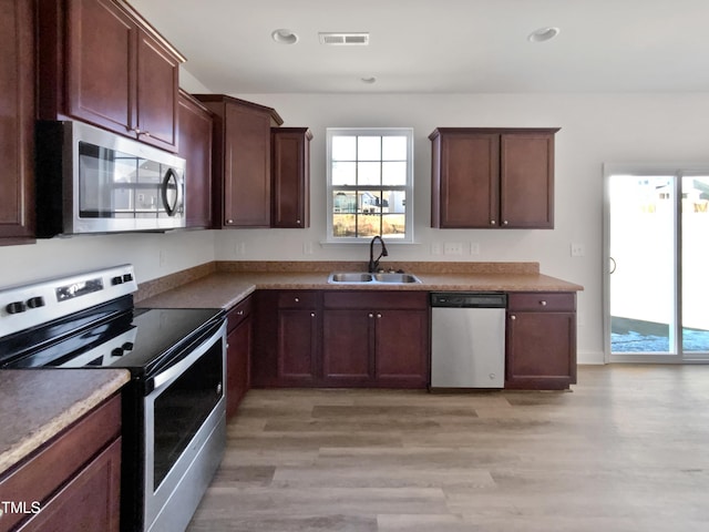 kitchen featuring sink, light hardwood / wood-style floors, dark brown cabinets, and appliances with stainless steel finishes