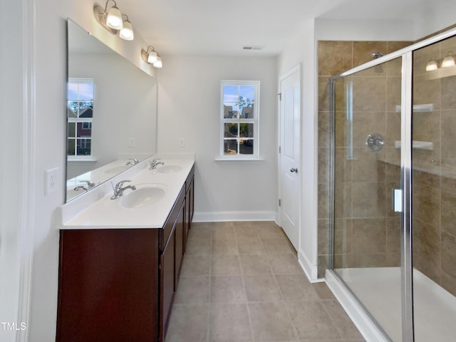 bathroom with tile patterned floors, vanity, a shower with door, and a wealth of natural light