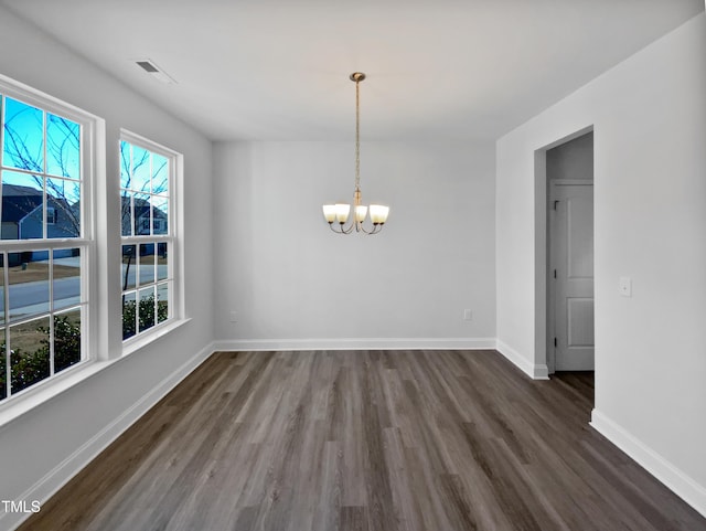 unfurnished dining area featuring a notable chandelier and dark hardwood / wood-style floors