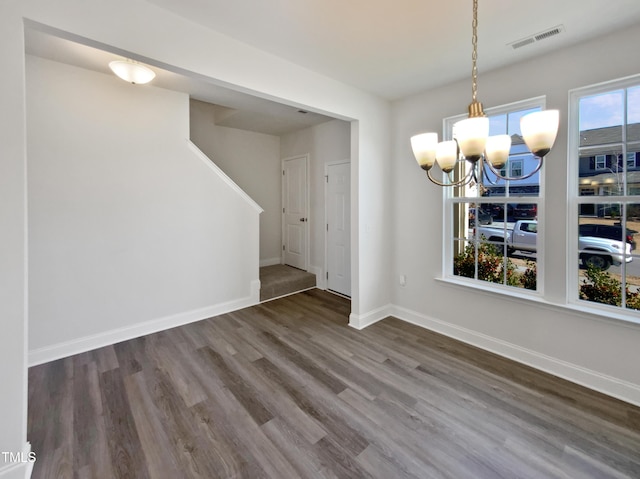 unfurnished dining area featuring a chandelier and dark hardwood / wood-style floors