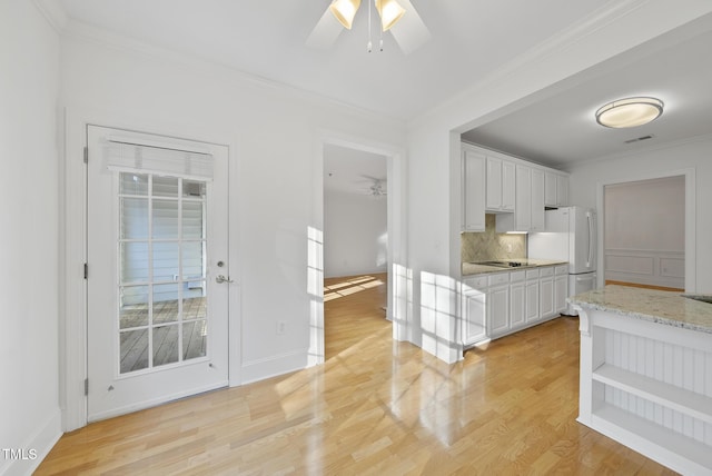 kitchen featuring light hardwood / wood-style flooring, white cabinets, tasteful backsplash, light stone counters, and white fridge