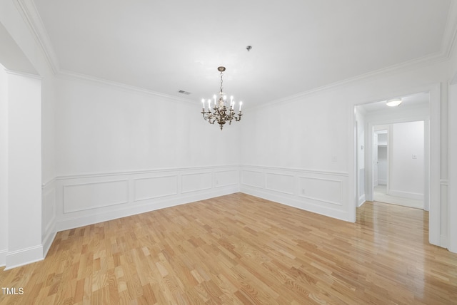 unfurnished room with ornamental molding, light hardwood / wood-style flooring, and a notable chandelier