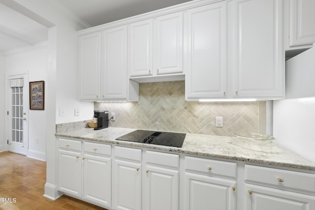 kitchen with white cabinetry, black electric stovetop, decorative backsplash, light wood-type flooring, and crown molding