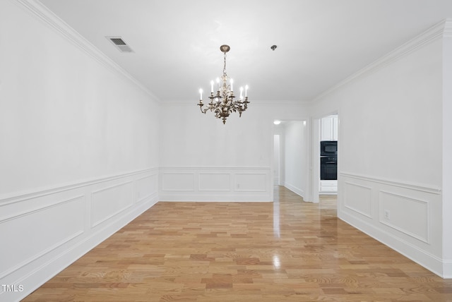 empty room with an inviting chandelier, ornamental molding, and light wood-type flooring