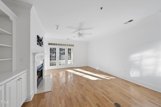 unfurnished living room with ceiling fan, ornamental molding, french doors, and light wood-type flooring