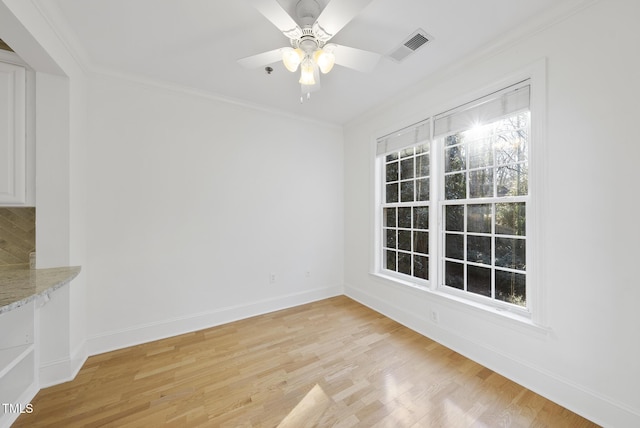 empty room featuring ceiling fan, a wealth of natural light, ornamental molding, and light hardwood / wood-style floors