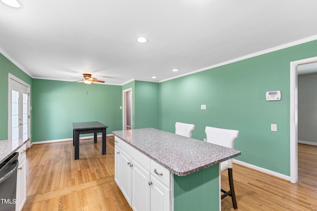 kitchen featuring a kitchen island, a breakfast bar, white cabinetry, dishwasher, and light hardwood / wood-style floors