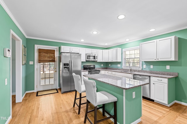 kitchen with a kitchen bar, sink, a kitchen island, stainless steel appliances, and white cabinets