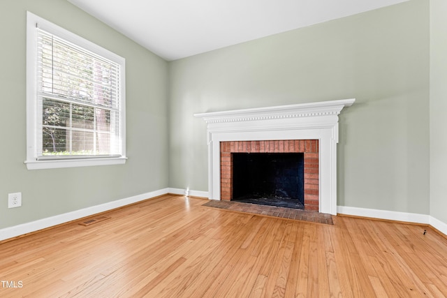 unfurnished living room featuring a brick fireplace and light wood-type flooring