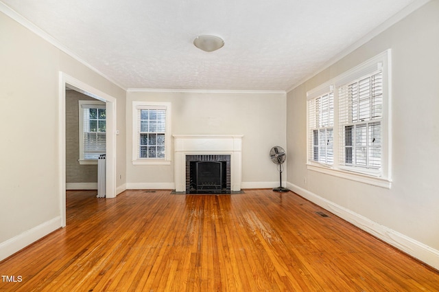 unfurnished living room featuring crown molding, hardwood / wood-style flooring, a fireplace, and a textured ceiling