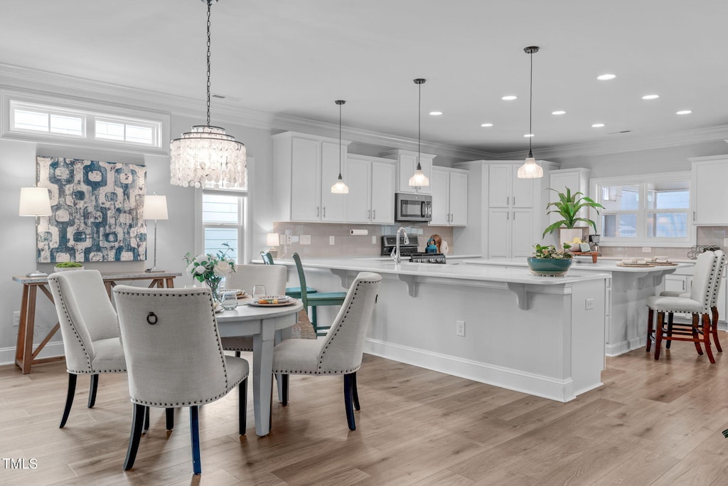 dining room with a wealth of natural light, crown molding, and light wood-type flooring