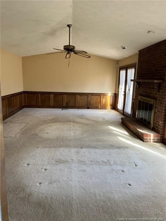 unfurnished living room with ceiling fan, light carpet, a fireplace, and a textured ceiling