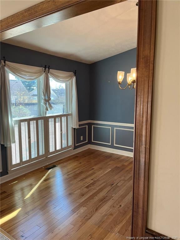 empty room featuring hardwood / wood-style flooring and a notable chandelier