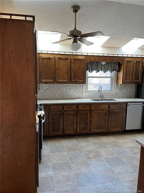 kitchen featuring sink, dishwasher, ceiling fan, a skylight, and range