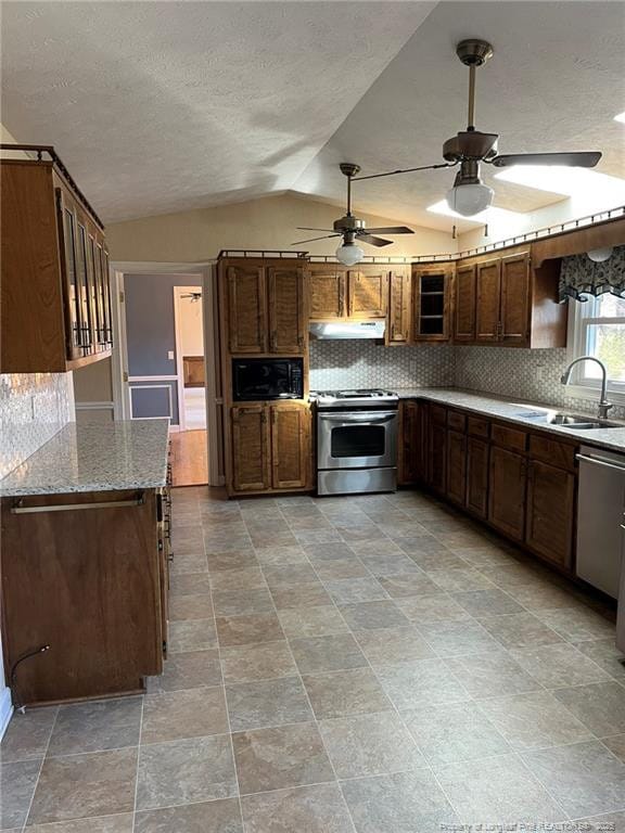 kitchen with light stone countertops, vaulted ceiling, decorative backsplash, appliances with stainless steel finishes, and sink