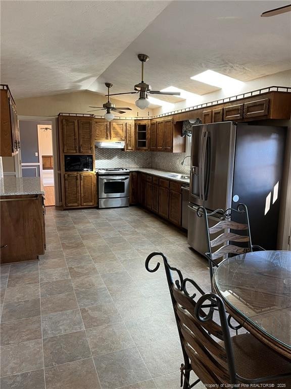 kitchen featuring appliances with stainless steel finishes, sink, lofted ceiling, and decorative backsplash