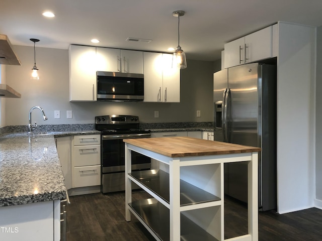 kitchen with a center island, wooden counters, sink, hanging light fixtures, and appliances with stainless steel finishes