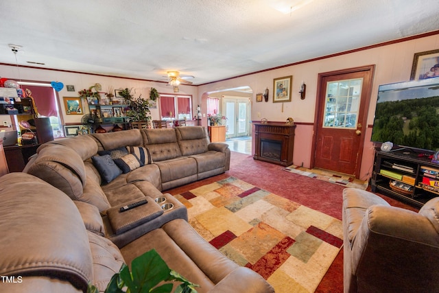 living room featuring ceiling fan, light colored carpet, a textured ceiling, and crown molding