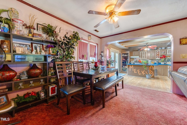 carpeted dining room featuring ceiling fan and crown molding