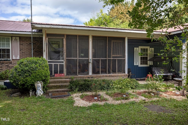 back of property featuring a lawn and a sunroom