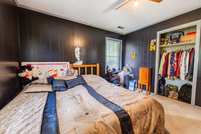 bedroom with a closet, ceiling fan, crown molding, and wood walls