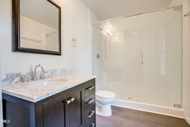 bathroom with hardwood / wood-style floors, vanity, toilet, and a shower with door