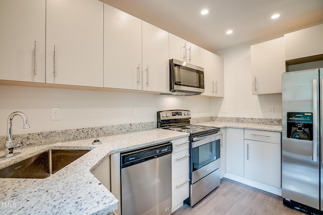 kitchen with white cabinetry, light stone countertops, sink, and stainless steel appliances