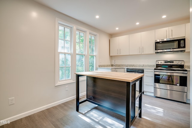 kitchen with stainless steel appliances, white cabinetry, light hardwood / wood-style floors, and sink