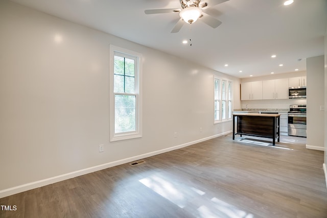 unfurnished living room featuring light wood-type flooring, plenty of natural light, and ceiling fan