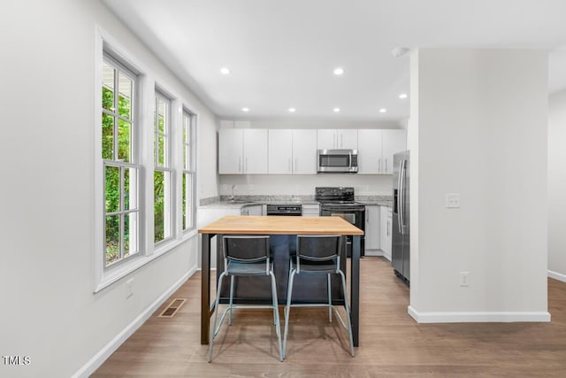 kitchen with stainless steel appliances, wooden counters, plenty of natural light, baseboards, and recessed lighting