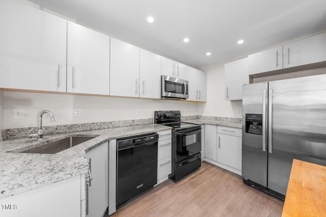 kitchen with black appliances, a sink, recessed lighting, light stone countertops, and light wood-style flooring
