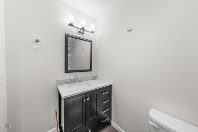 bathroom featuring toilet, baseboards, vanity, and wood finished floors