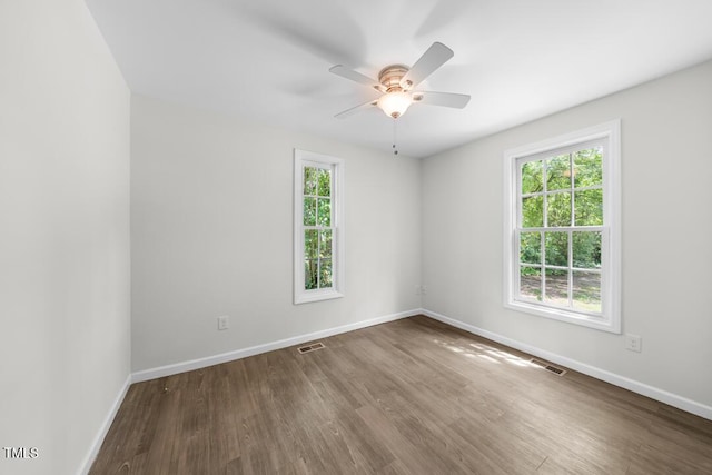 empty room with wood finished floors, a ceiling fan, and baseboards
